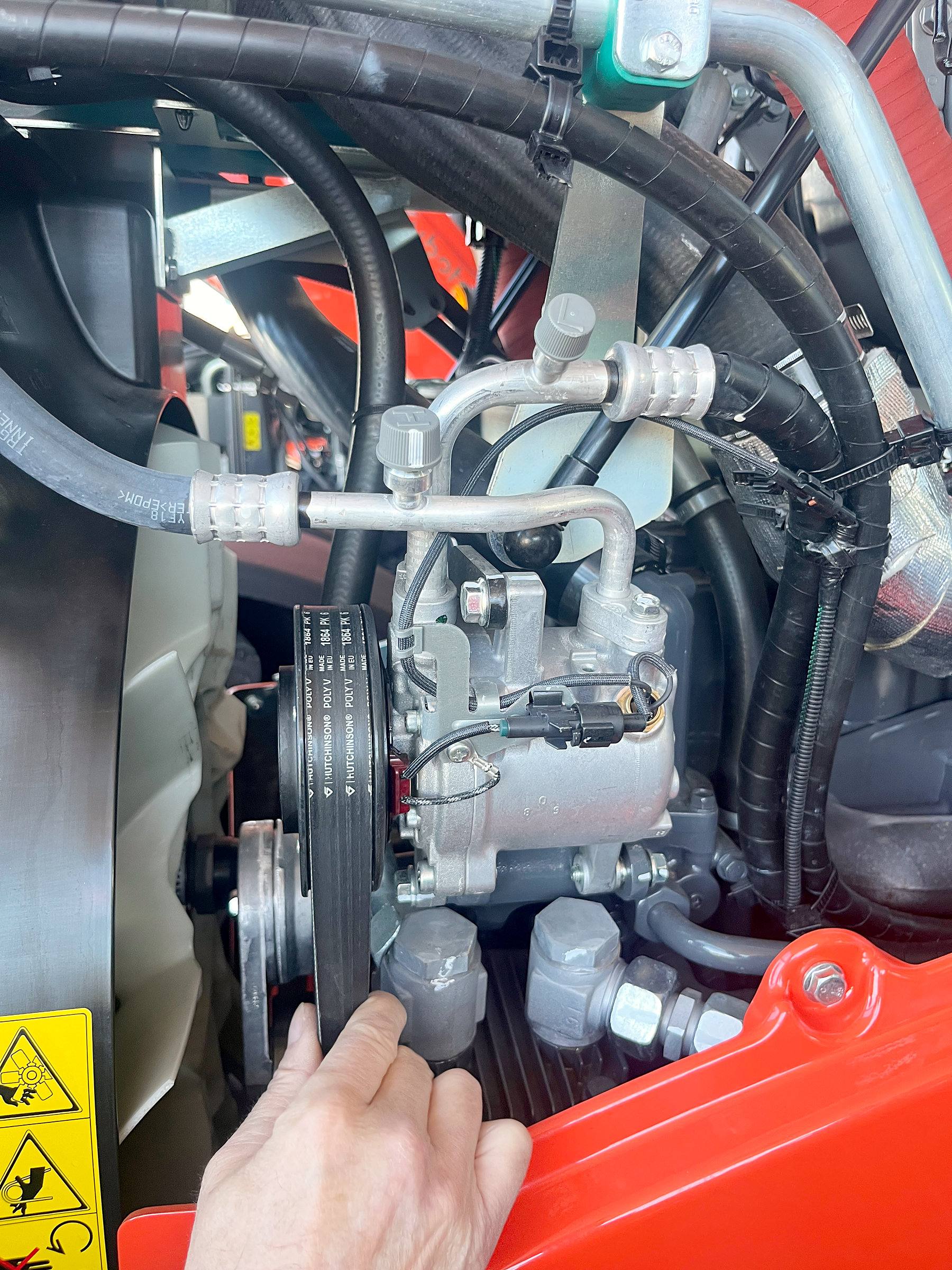 Montaje de un compresor de aire acondicionado en el motor de un tractor.